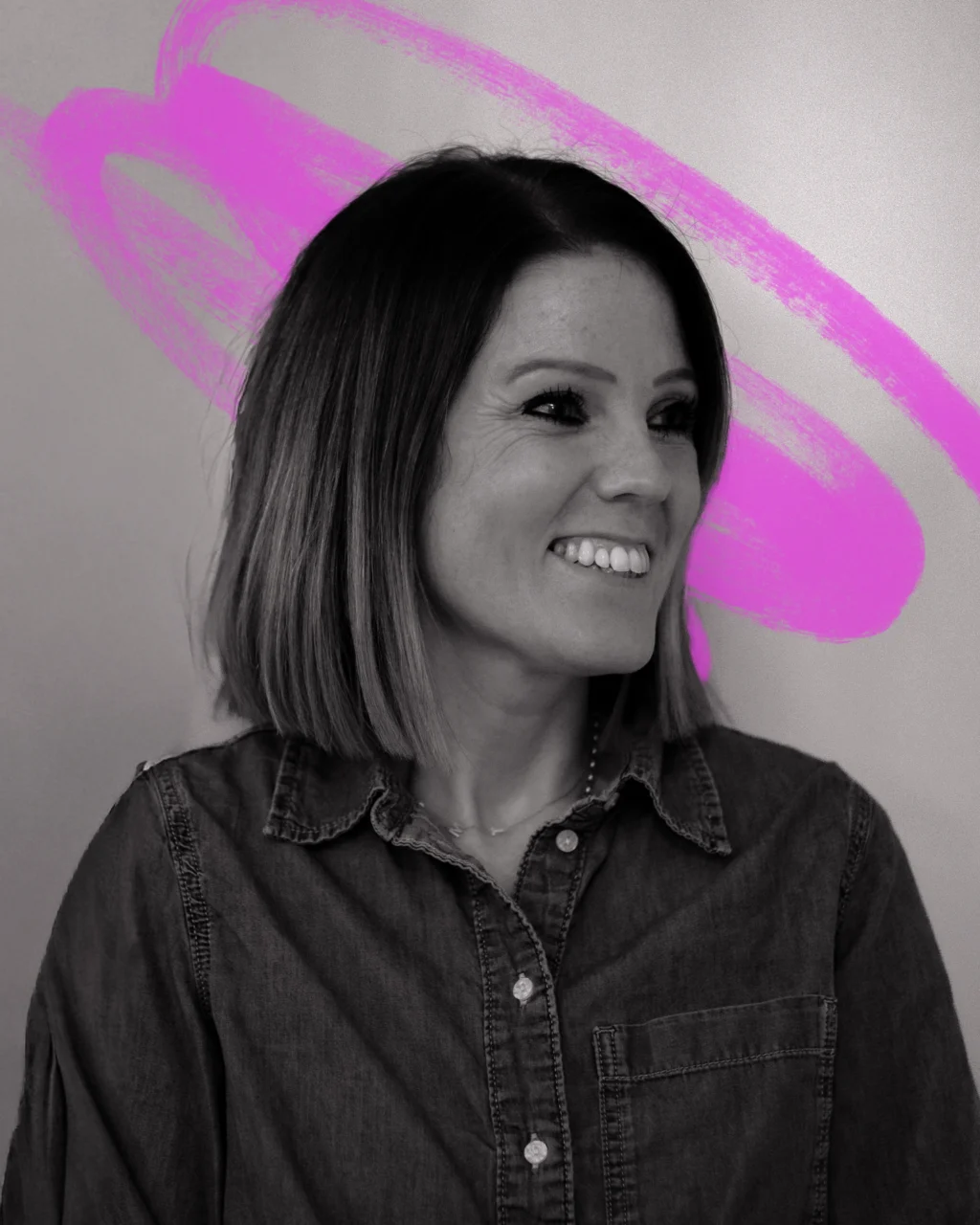 a closeup black and white portrait of a woman looking to the right, smiling. she has light hair cut into a sharp bob. Behind her is a hand-drawn scribble in neon pink.