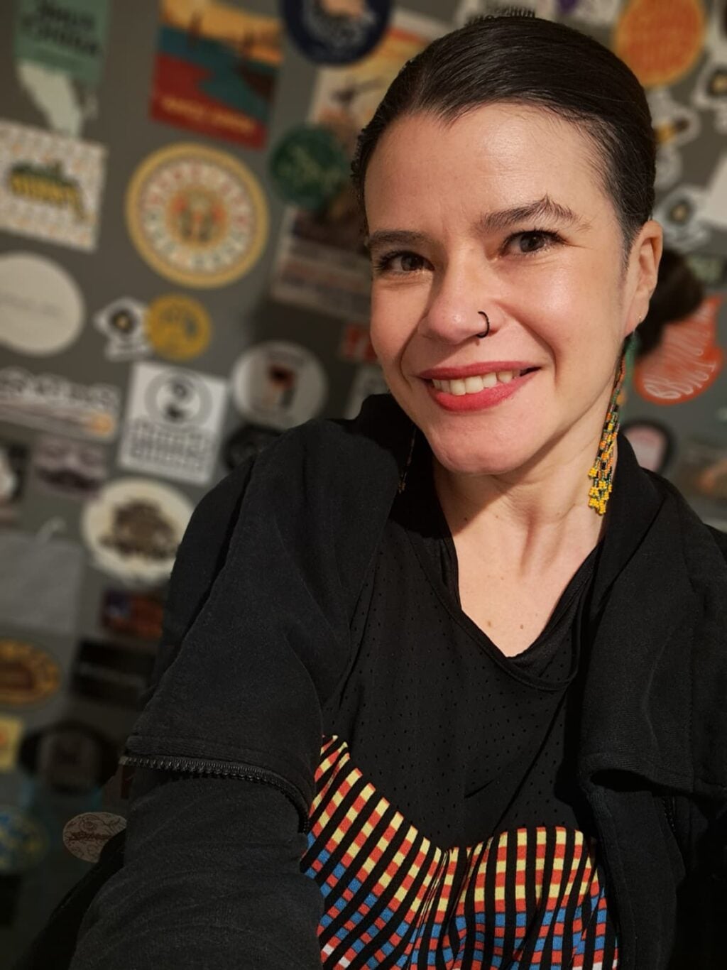 A selfie of a woman in her late twenties, wearing a black and red dress.