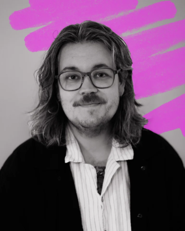 a black and white portrait of a man with shaggy, shoulder length hair, a short moustache and boxy glasses. Behind him is a hand-drawn scribble in neon pink.