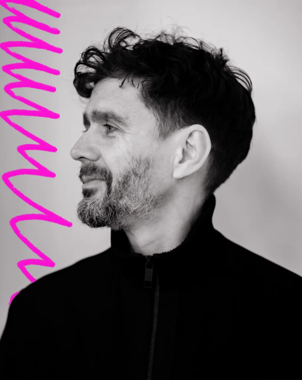 a close up black and white portrait of a man with short dark curly hair looking off to the left. Next to him is a hand-drawn neon pink scribble.